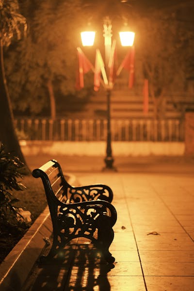 A serene bench under warm streetlights in a quiet park, evoking a romantic evening in Hanoi.